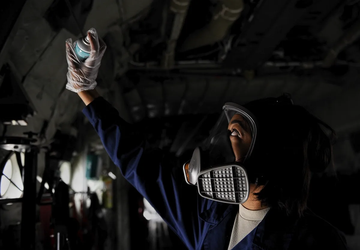 Pest-control worker inspecting an overhead utility area